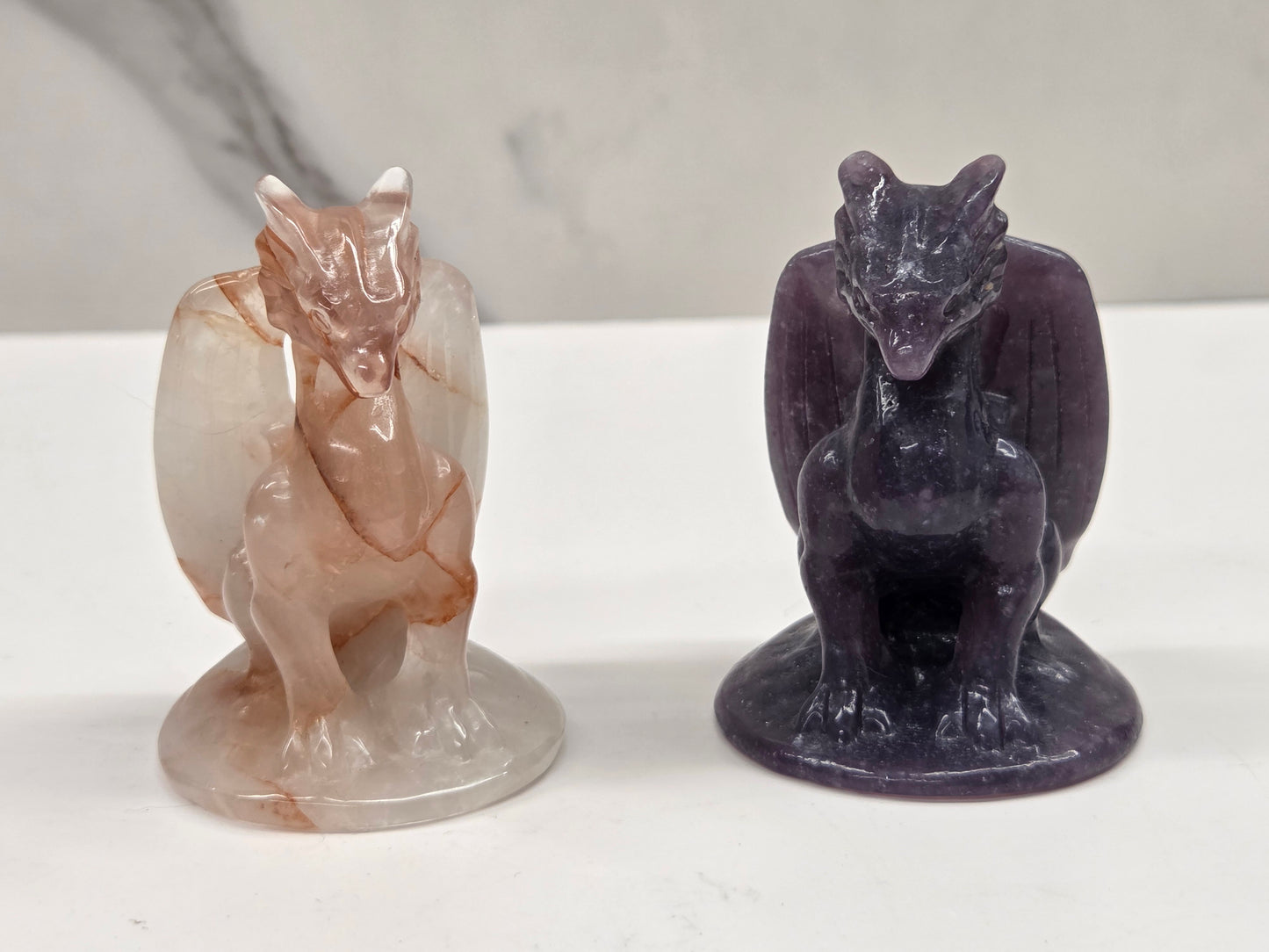 Two stone carvings a dragon on a white surface with a gray background.