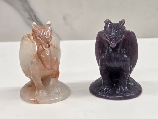 Two stone carvings a dragon on a white surface with a gray background.