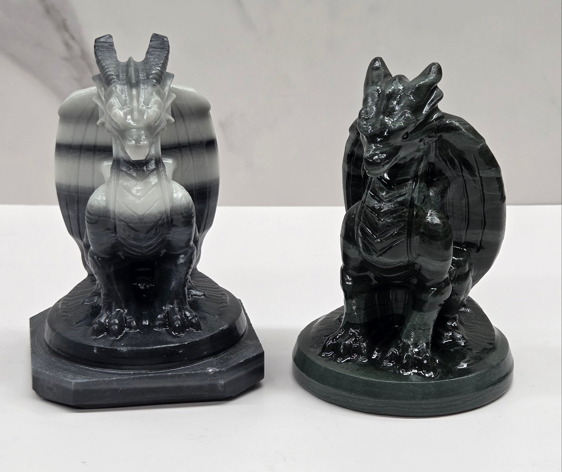 Set of 2 crystal dragon sculptures, one black and white striped, one green, on a white background