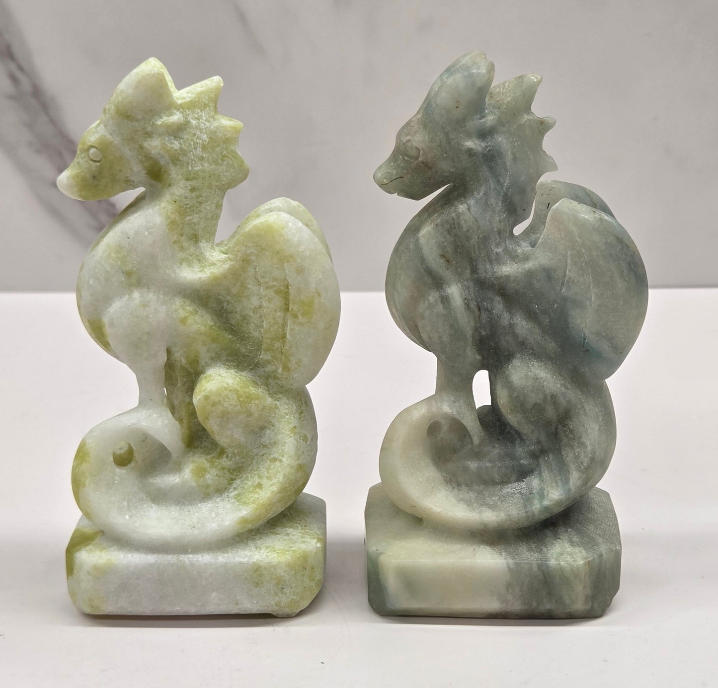 Set of 2 crystal dragon sculptures, one Lime Jade, one Blue Calcite, on a white background
