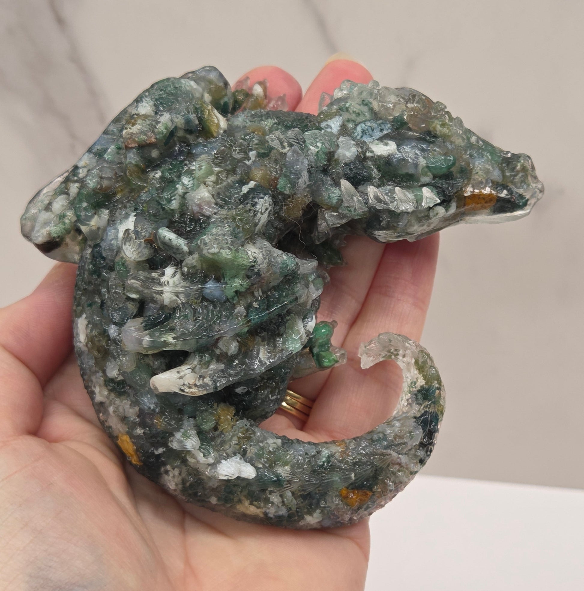 Hand holding resin with crystal chip carving of a dragon on a white background