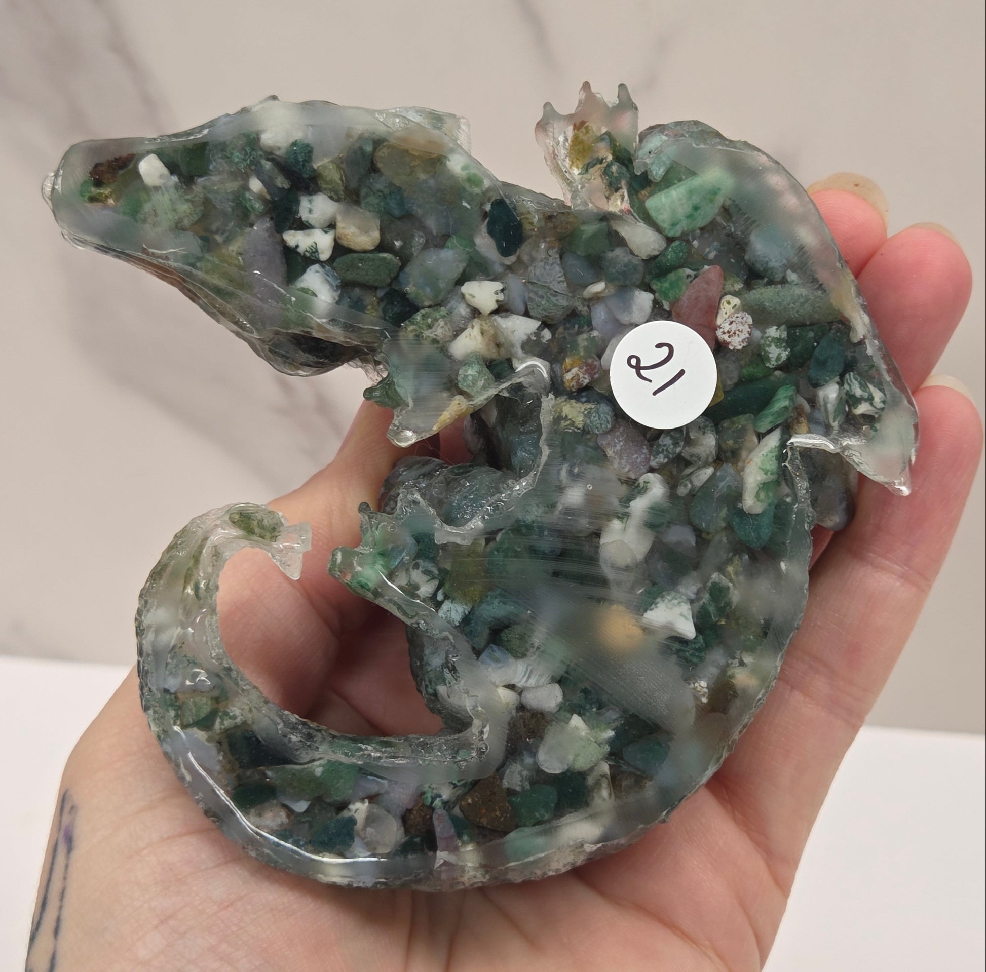 Hand holding resin with crystal chip carving of a dragon on a white background