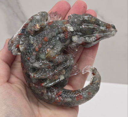 Hand holding resin with crystal chip carving of a dragon on a white background
