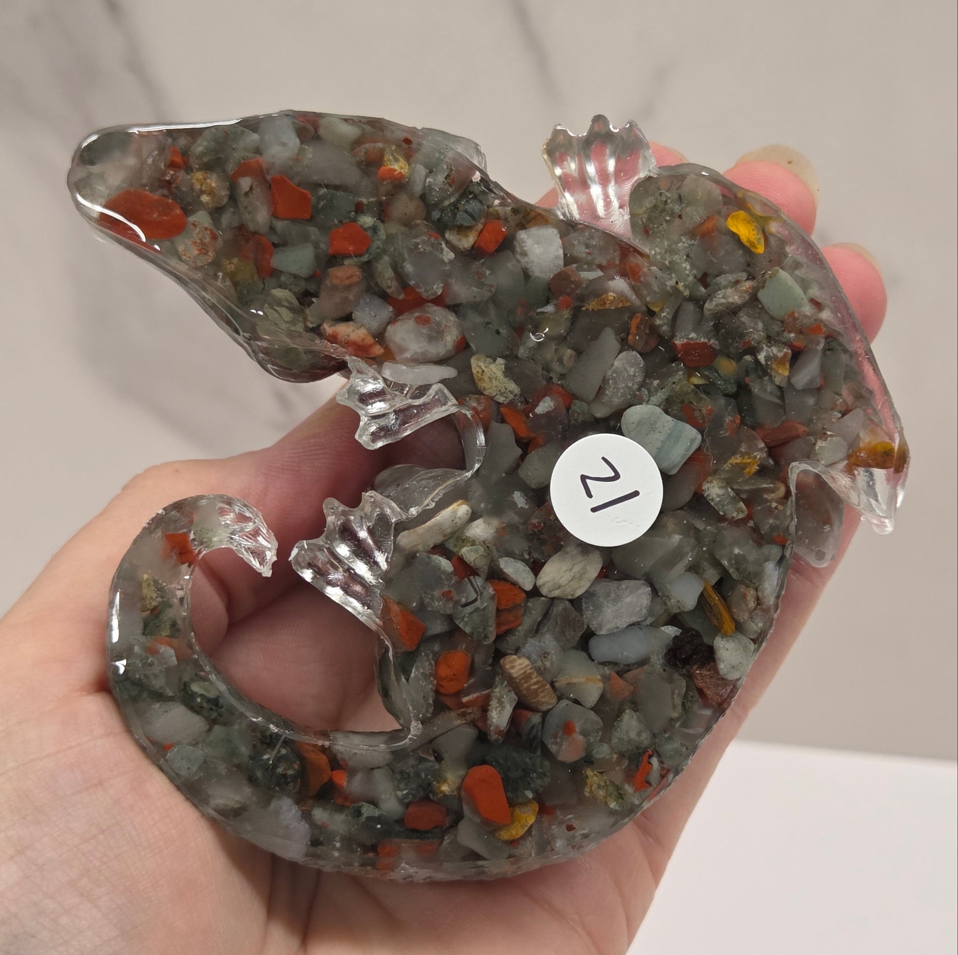 Hand holding resin with crystal chip carving of a dragon on a white background