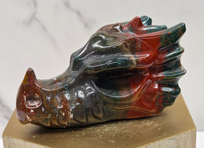 Decorative dragon head stone carving on a wooden stand with a plain background