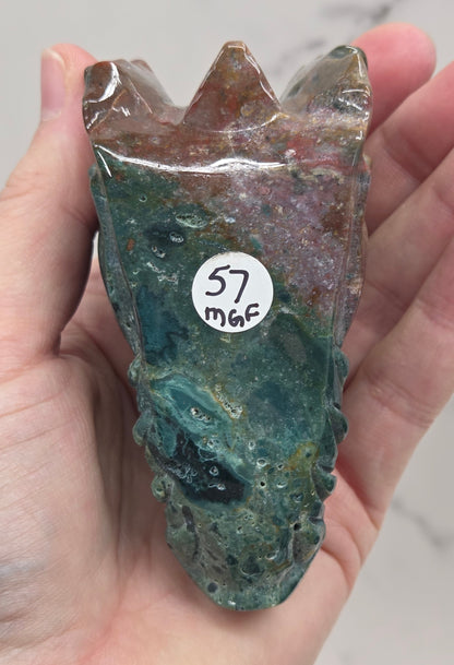 Decorative dragon head stone carving on a wooden stand with a plain background
