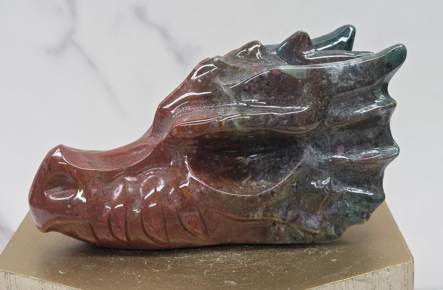 Decorative dragon head stone carving on a wooden stand with a plain background