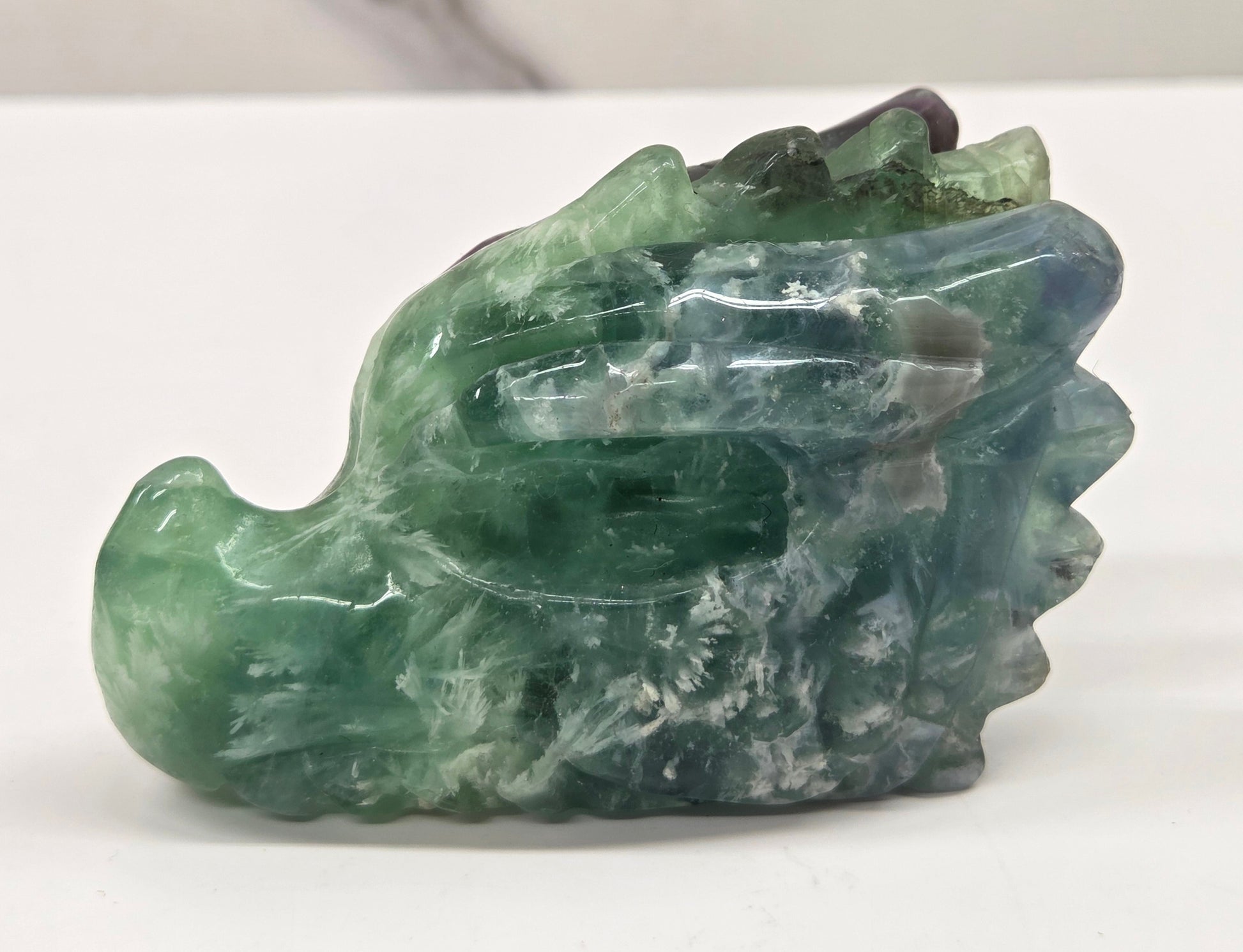 Green crystal dragon head sculpture on a white background