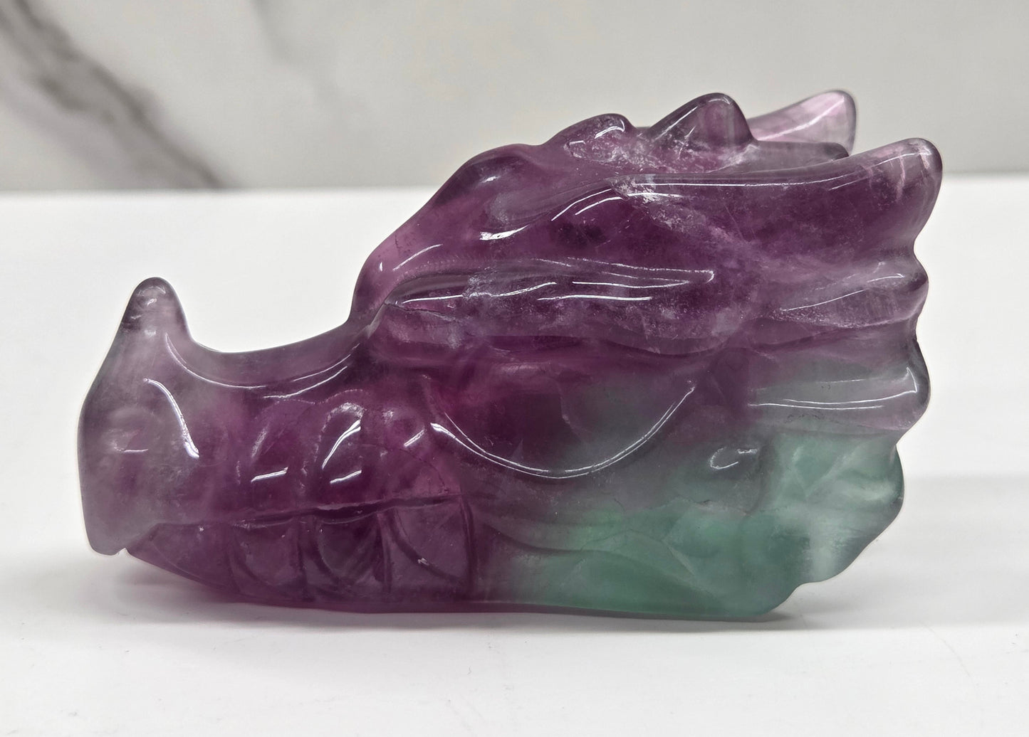 Fluorite dragon head sculpture on a white surface