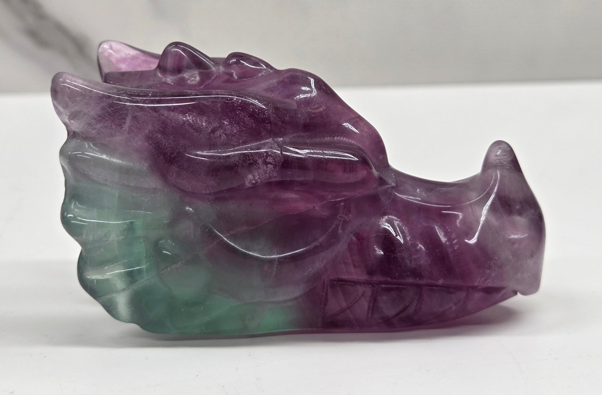 Fluorite dragon head sculpture on a white surface