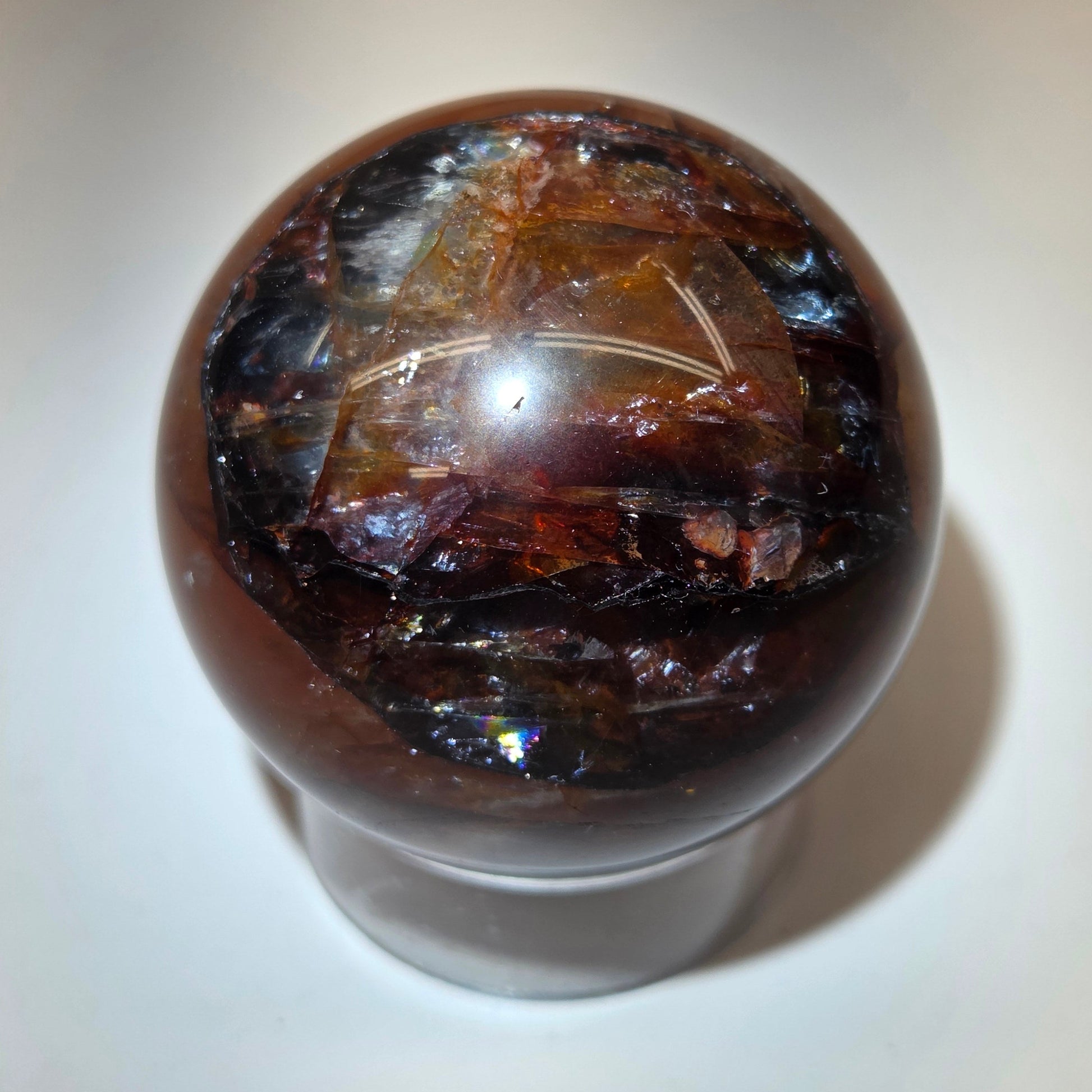 polished Fire Quartz crystal sphere on a white background