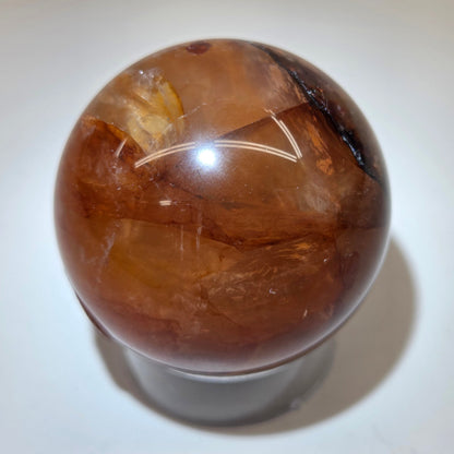 polished Fire Quartz crystal sphere on a white background