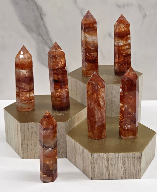 Fire Quartz crystal points on a wooden stand against a marble background