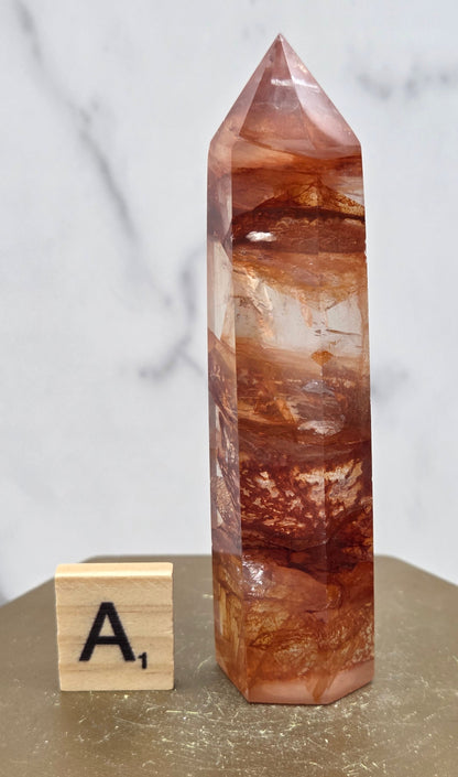 Fire Quartz crystal point with 'A1' label on a marble surface