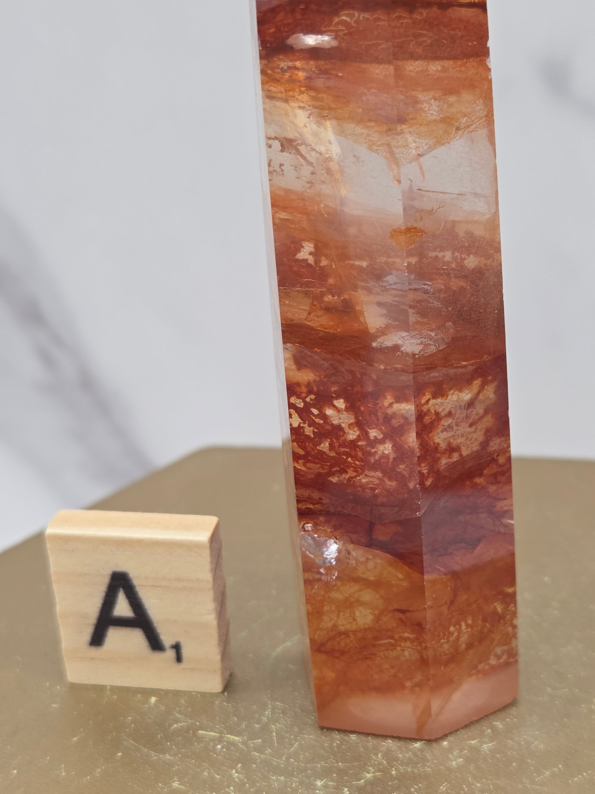 Fire Quartz crystal point with 'A1' label on a marble surface