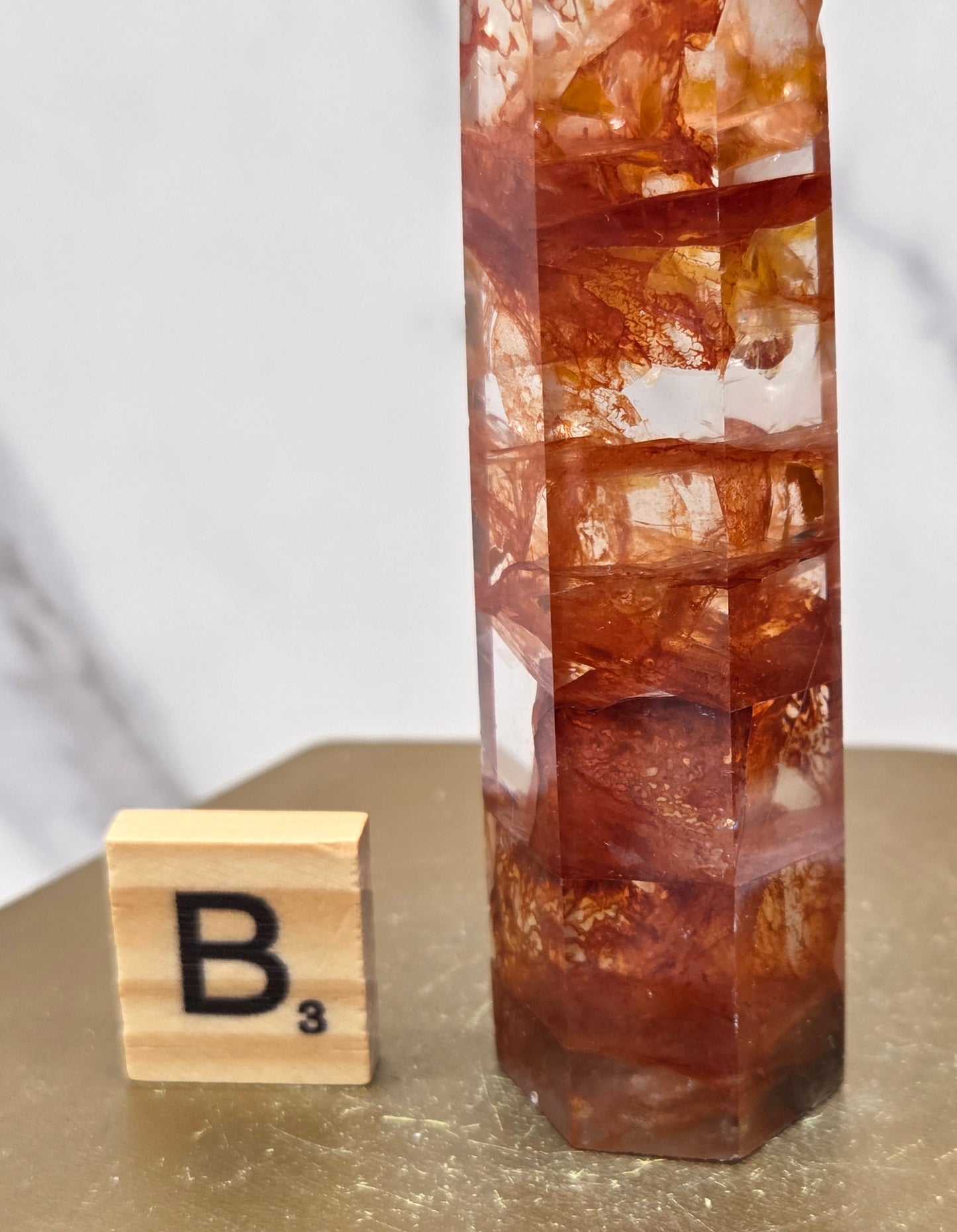 Fire Quartz crystal point with 'B3' label on a marble surface
