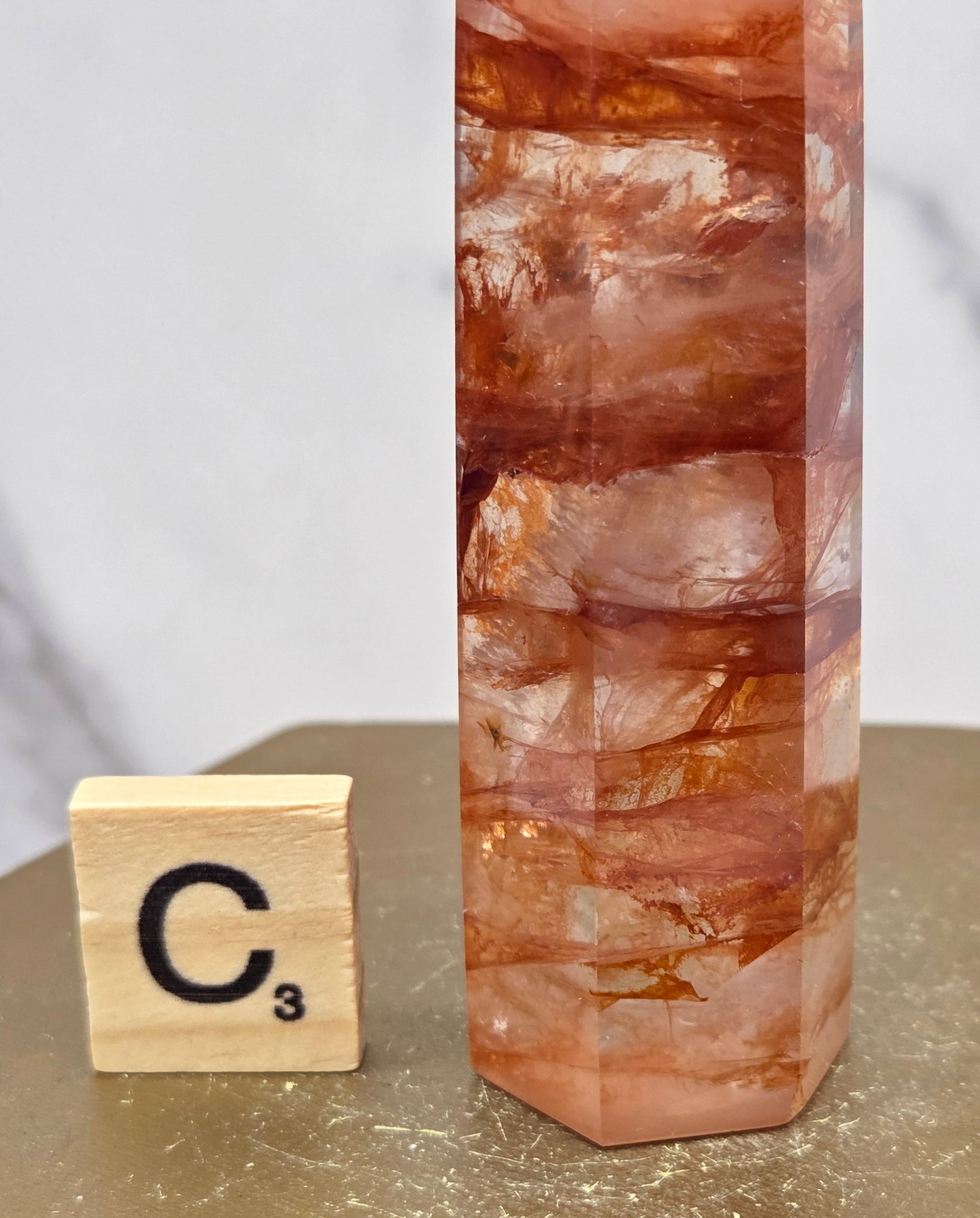 Fire Quartz crystal point with 'C3' label on a marble surface