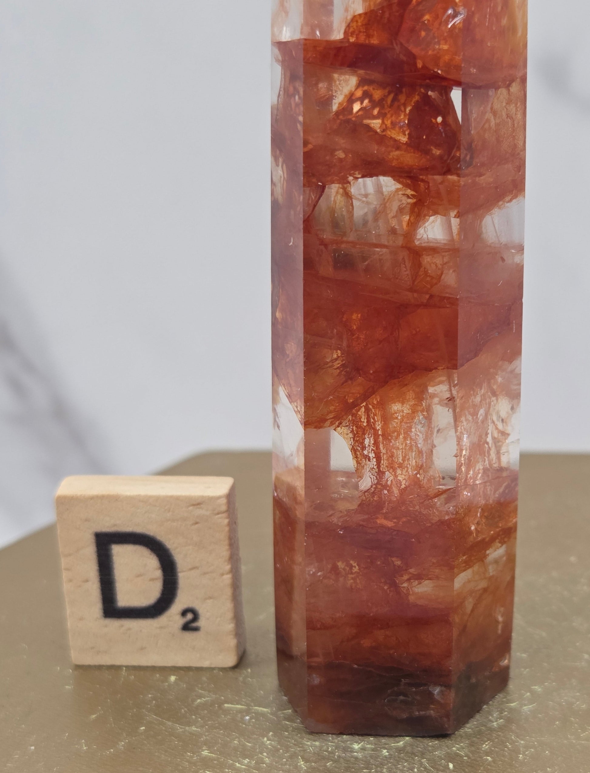 Fire Quartz crystal point with 'D2' label on a marble surface