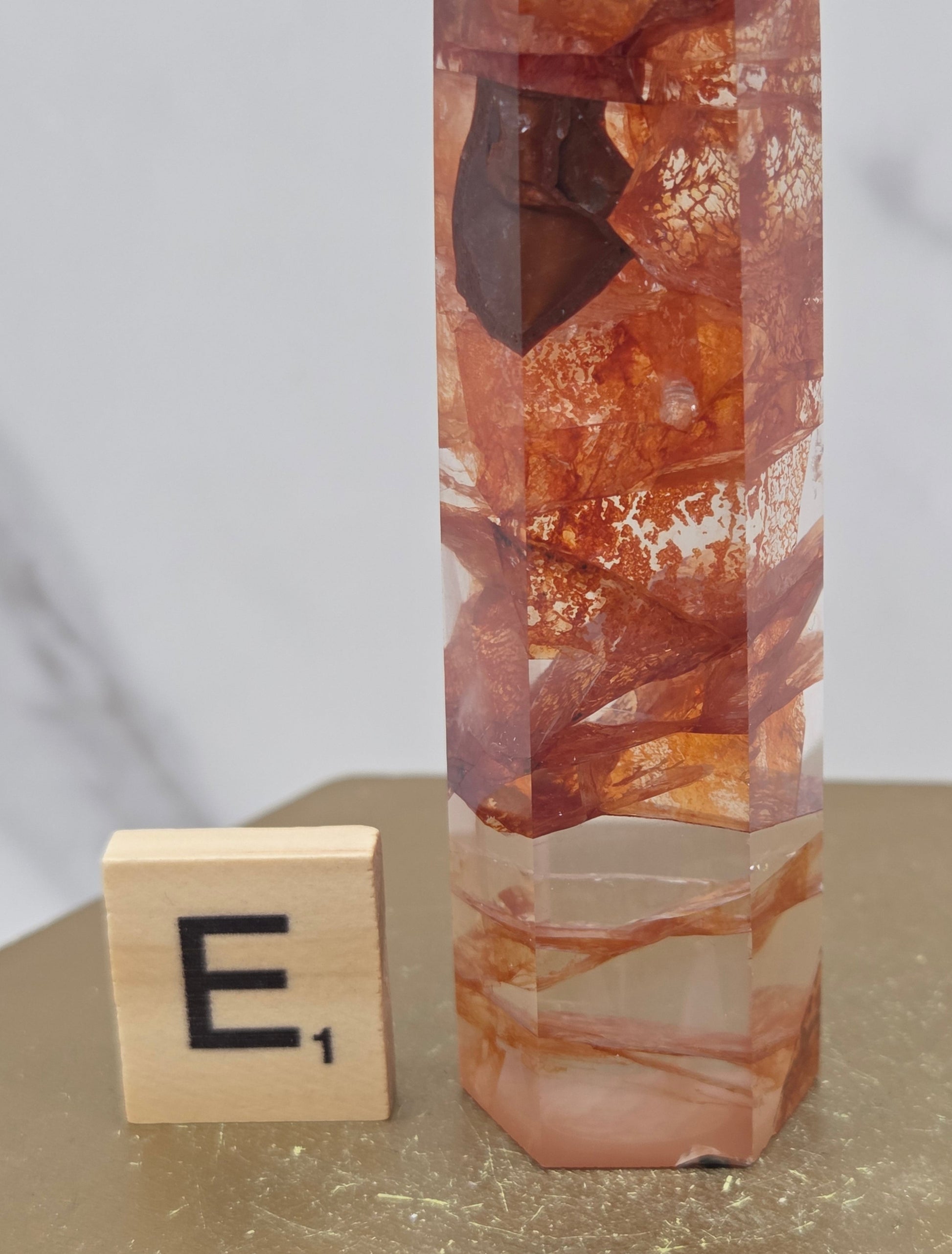 Fire Quartz crystal point with 'E1' label on a marble surface