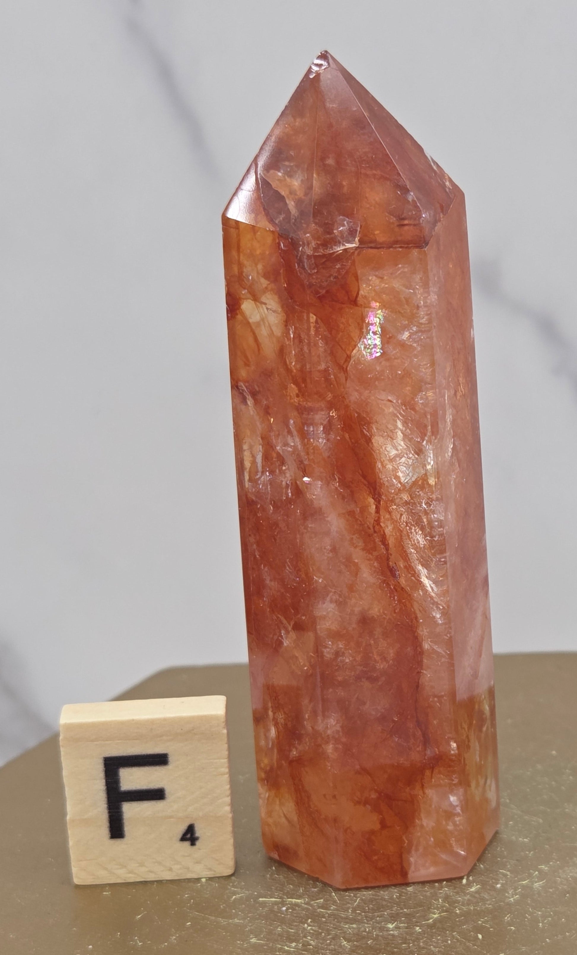 Fire Quartz crystal point with 'F4' label on a marble surface