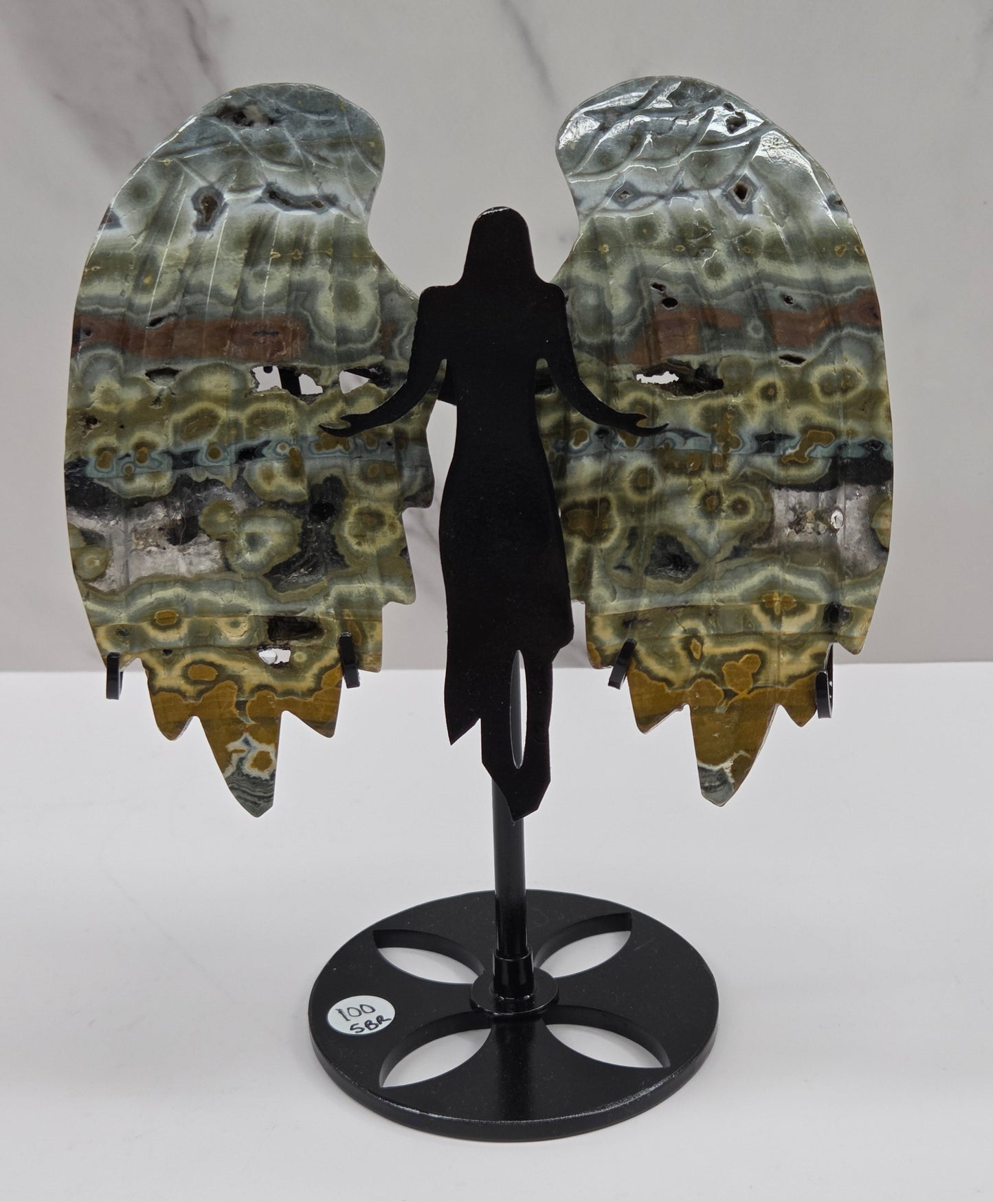 Multi-colored and patterned Jasper angel wings on a black stand against a white background