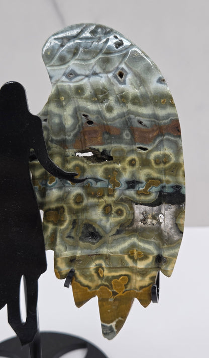 Multi-colored and patterned Jasper angel wings on a black stand against a white background