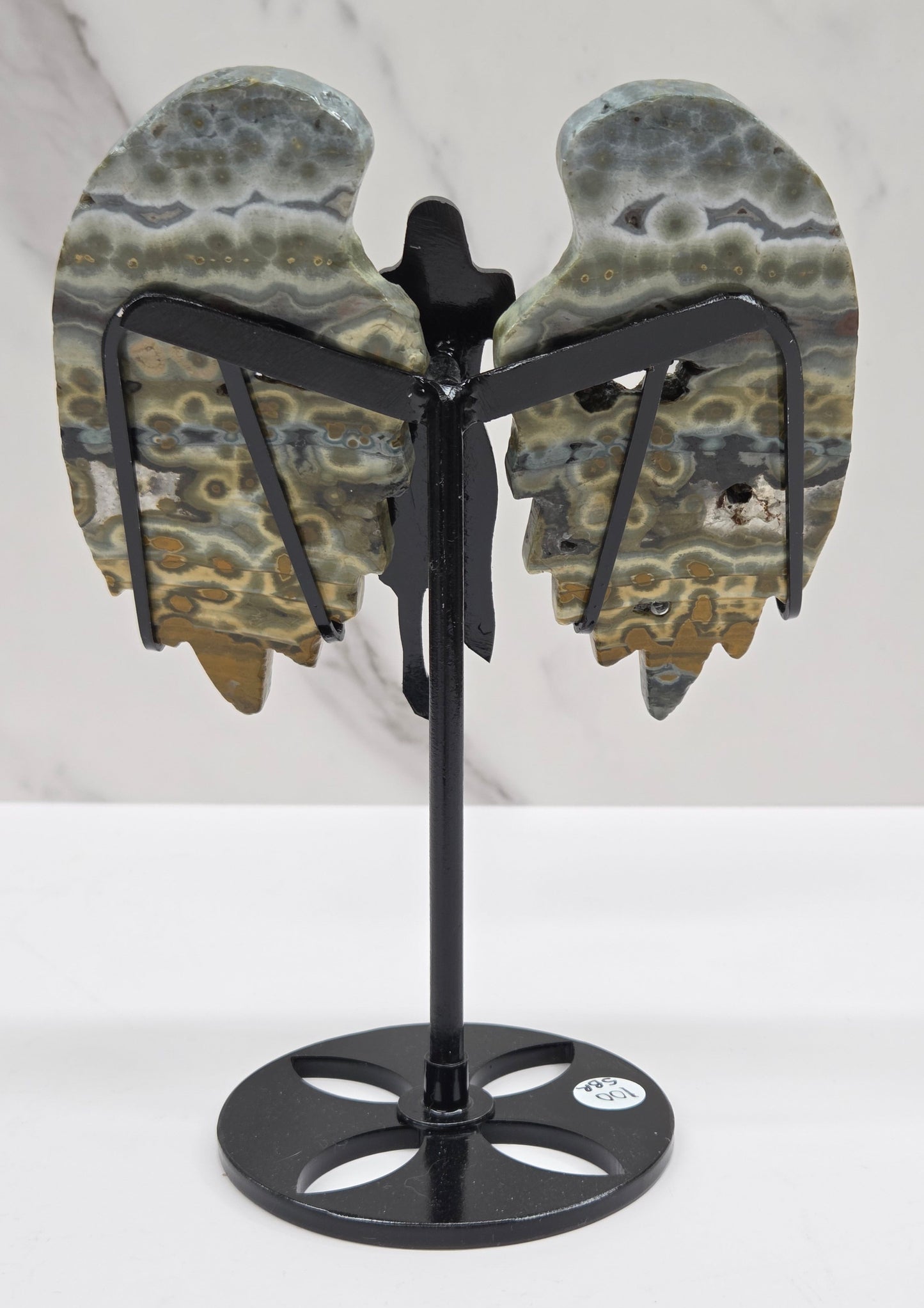 Multi-colored and patterned Jasper angel wings on a black stand against a white background