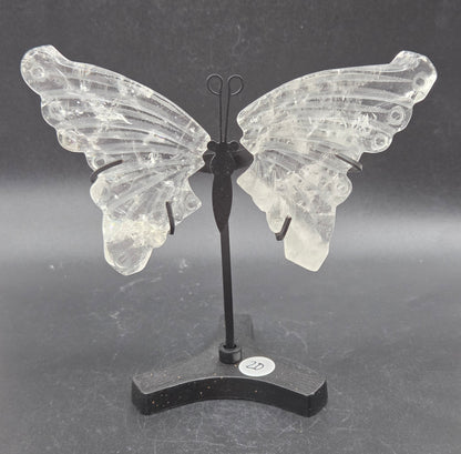 Decorative clear quartz butterfly wings on a black stand on a dark background