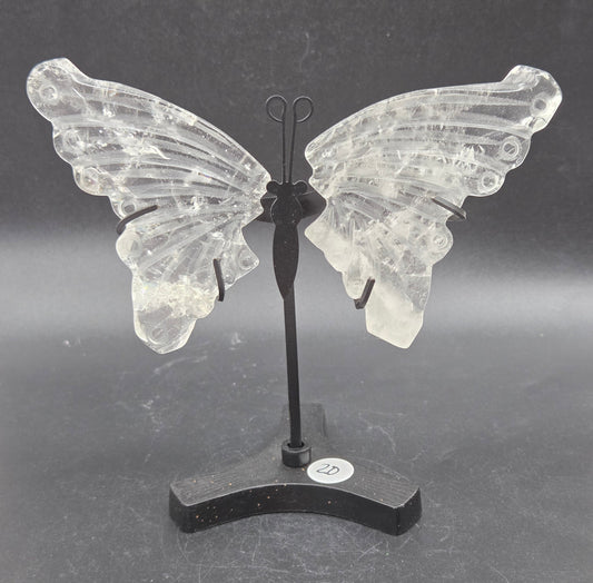 Decorative clear quartz butterfly wings on a black stand on a dark background