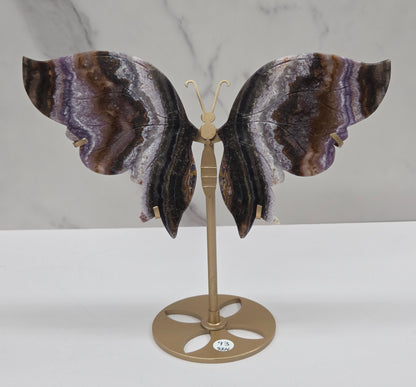 Decorative butterfly with banded crystal wings on a gold metal frame on a marble background