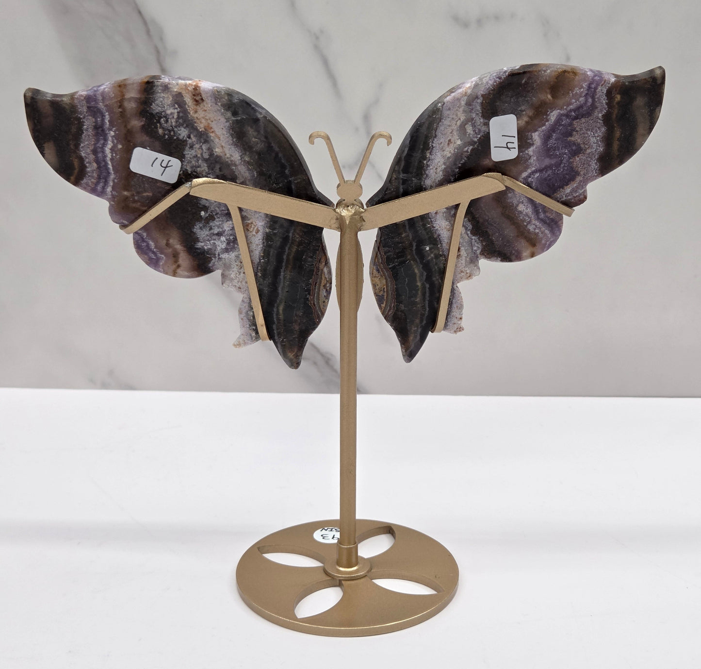 Decorative butterfly with banded crystal wings on a gold metal frame on a marble background