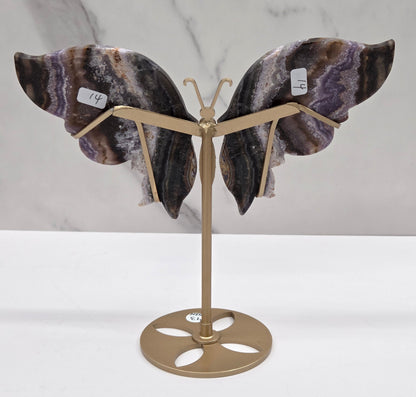 Decorative butterfly with banded crystal wings on a gold metal frame on a marble background