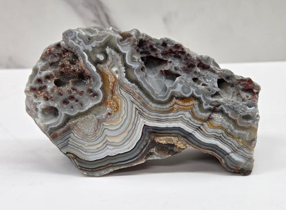 Laguna lace agate specimen with colorful banding on a neutral background