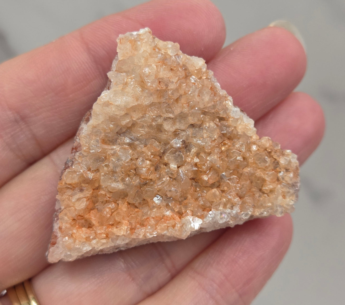 Hand holding a calcite specimen with a neutral background