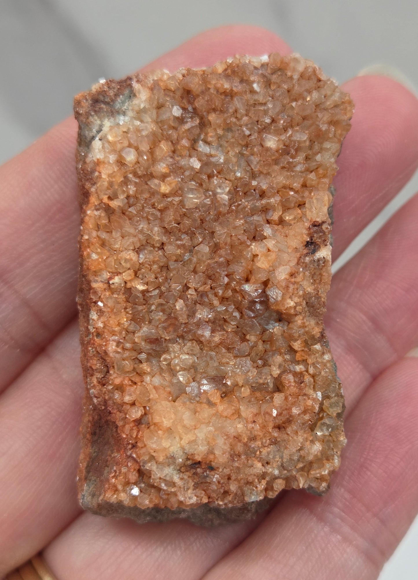 Hand holding a calcite specimen with a neutral background