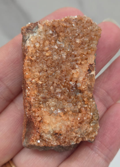 Hand holding a calcite specimen with a neutral background