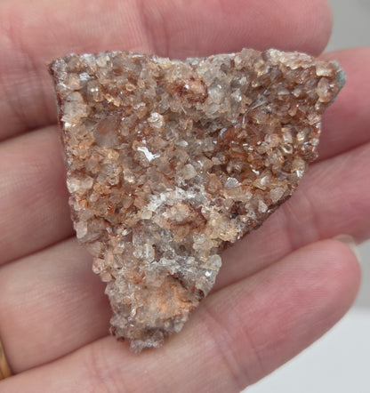 Hand holding a calcite specimen with a neutral background