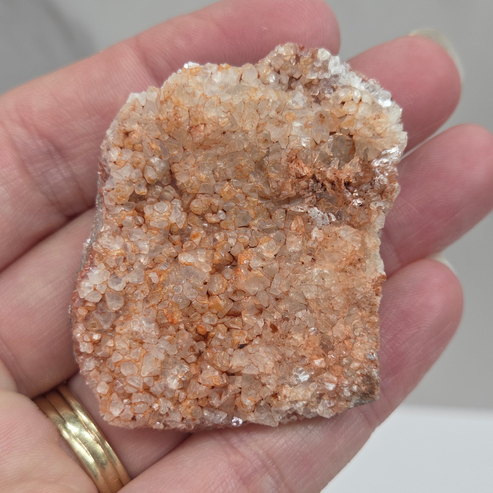 Hand holding a calcite specimen with a neutral background