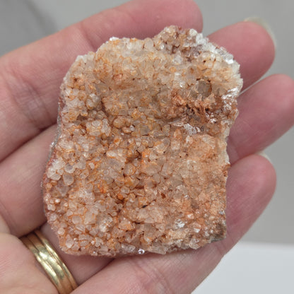 Hand holding a calcite specimen with a neutral background