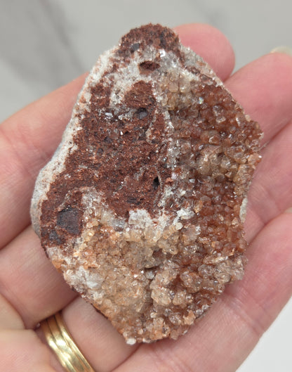 Hand holding a calcite specimen with a neutral background