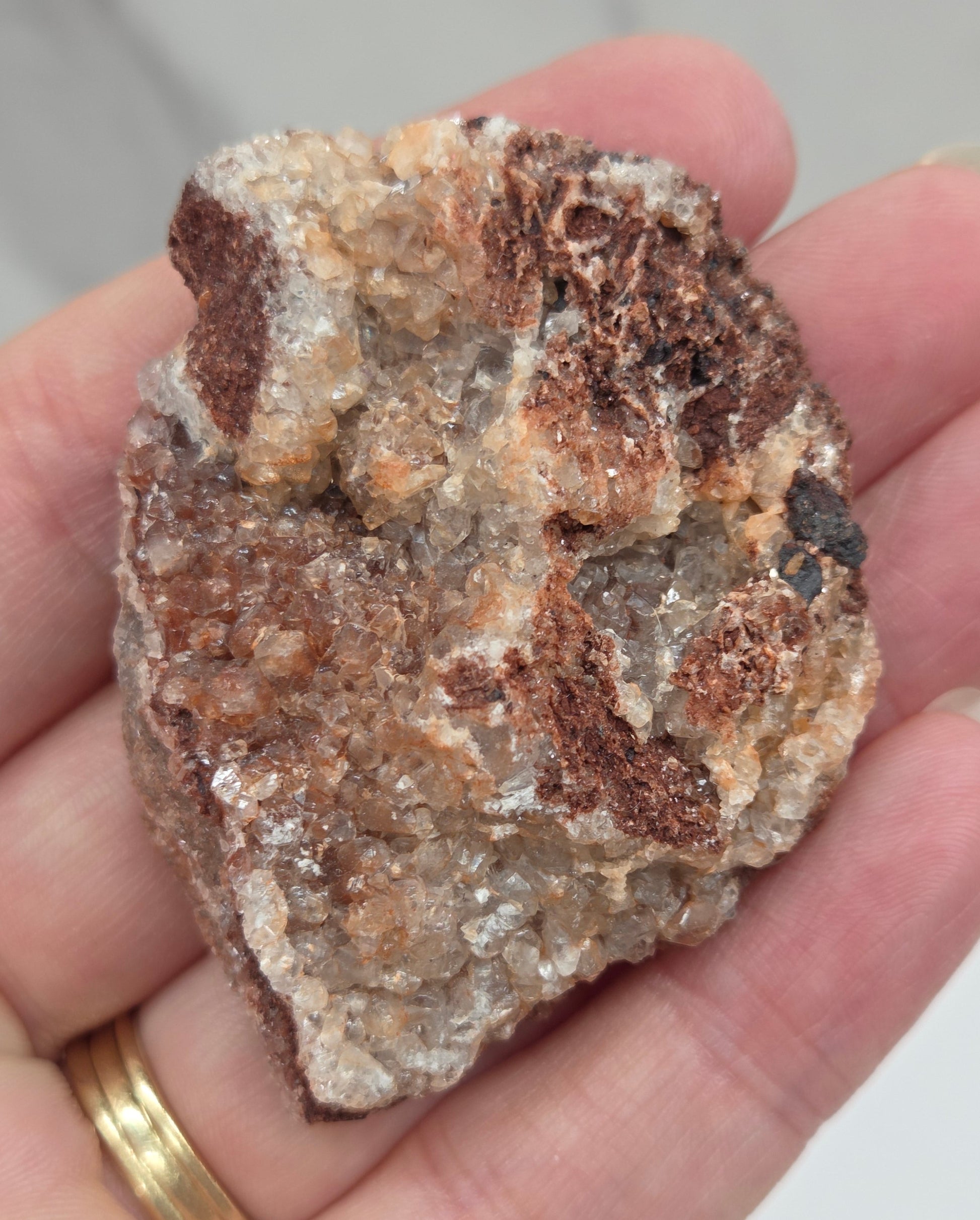 Hand holding a calcite specimen with a neutral background