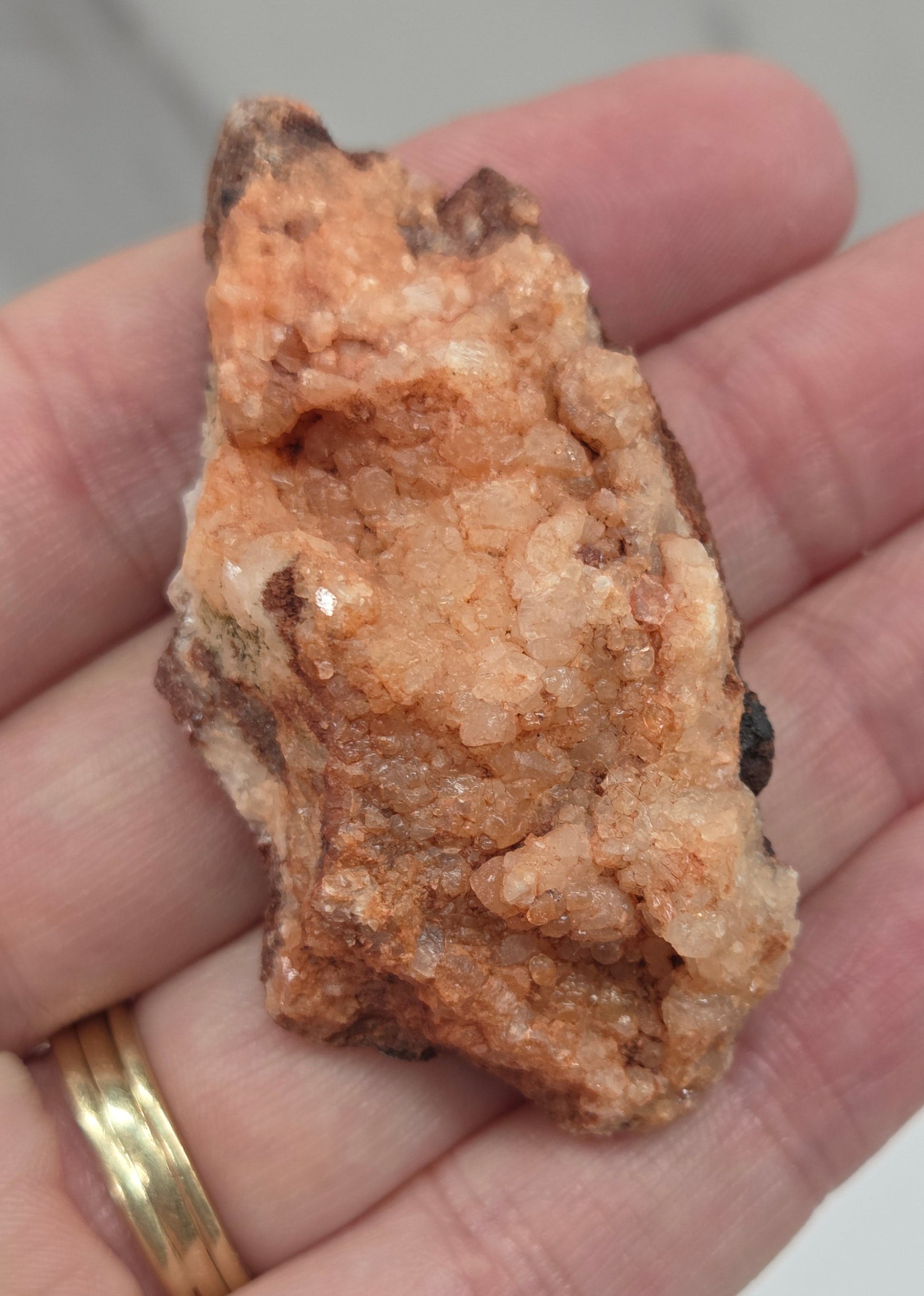 Hand holding a calcite specimen with a neutral background