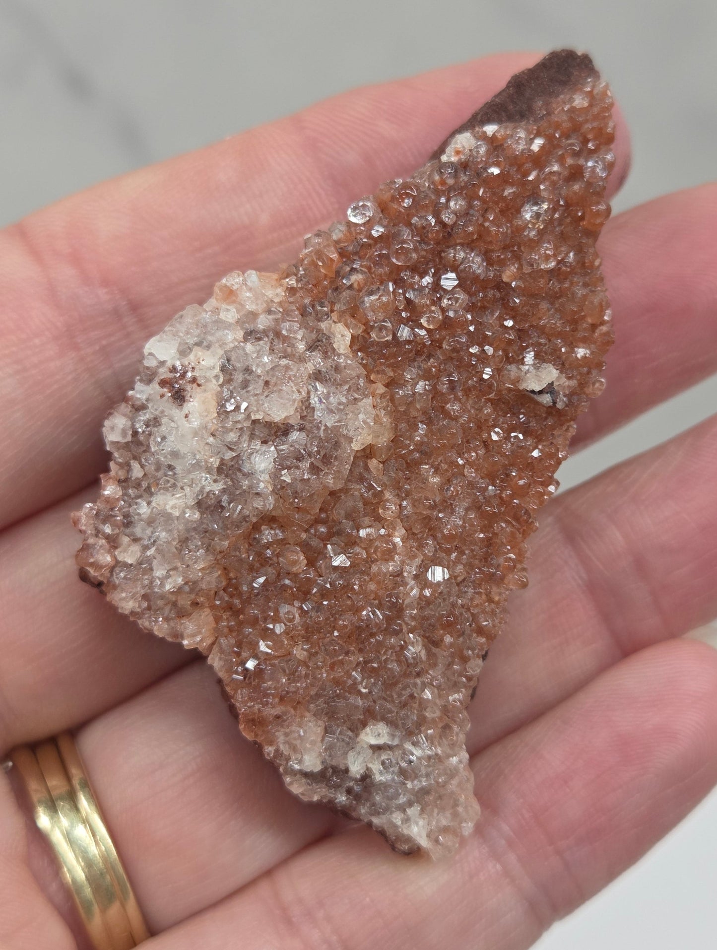 Hand holding a calcite specimen with a neutral background