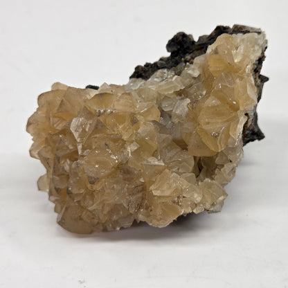 Calcite crystal specimens on a white background, with varying sizes and hues, some with a golden color and others with a darker, clouded appearance.