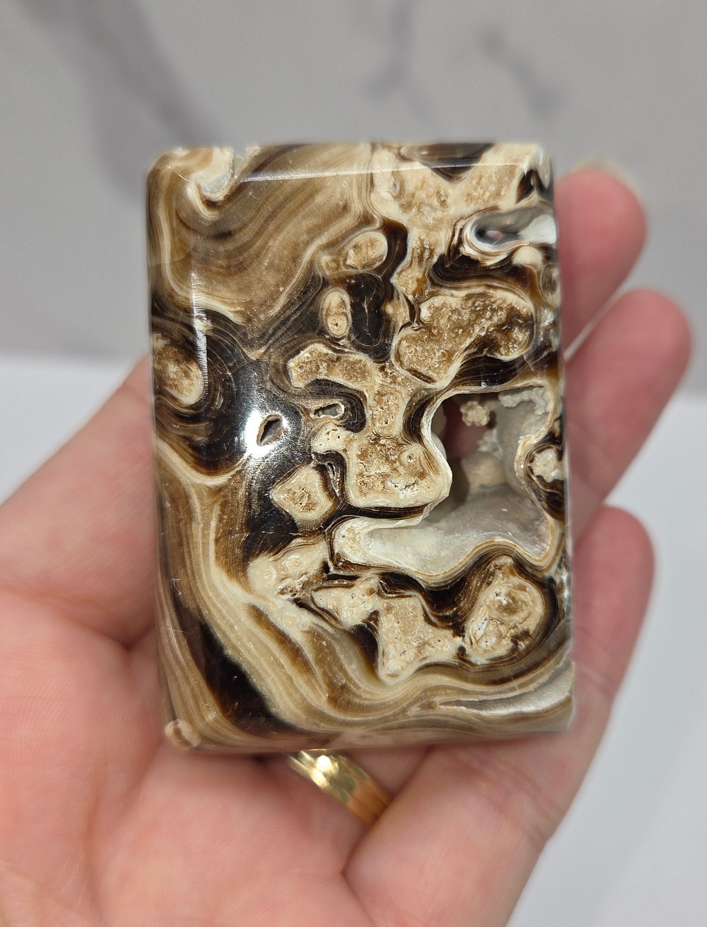 Hand holding a marbled rectangular object against a neutral background
