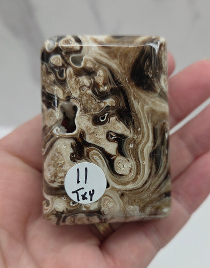 Hand holding a marbled stone with a  label, against a neutral background