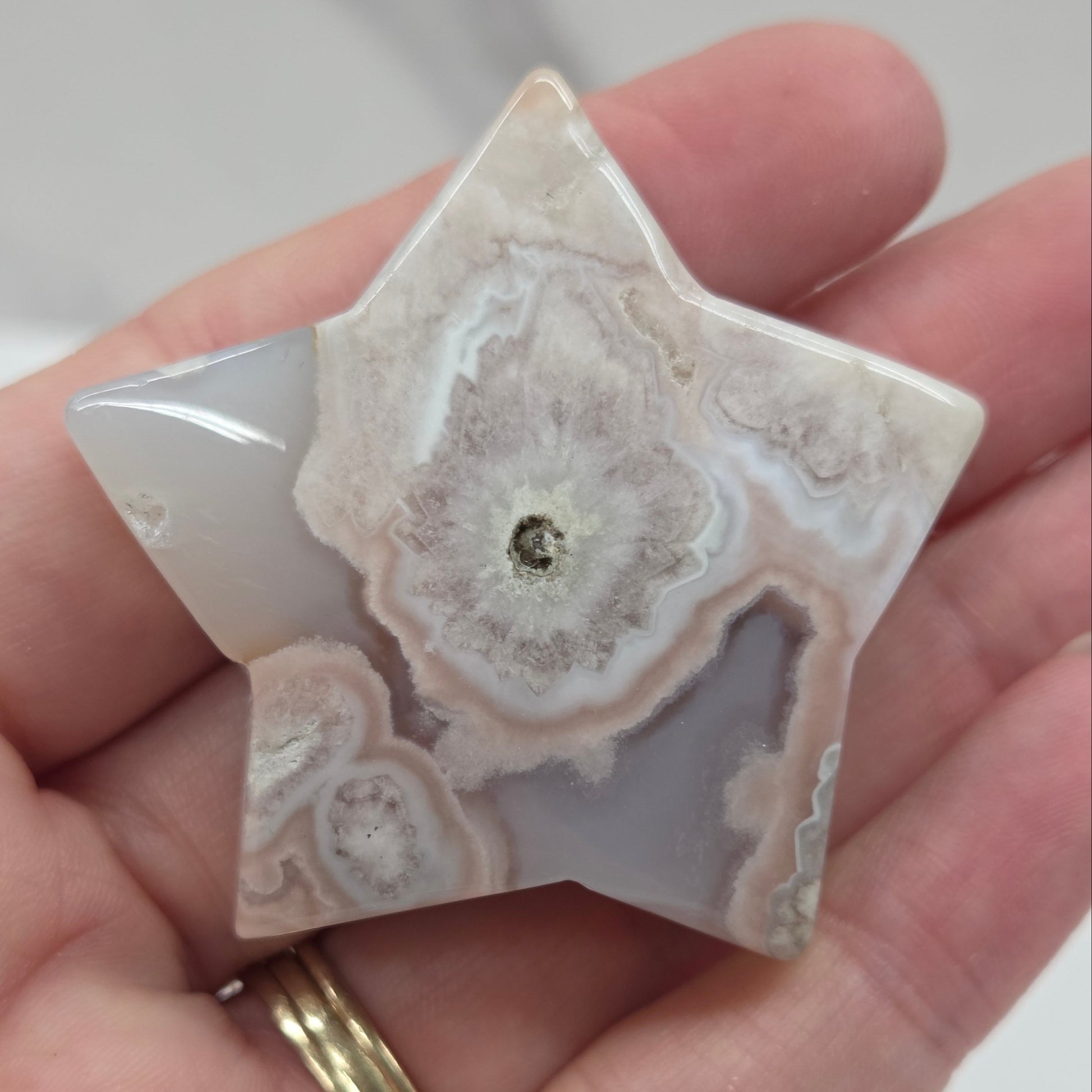 Hand holding a star-shaped agate stone against a white background