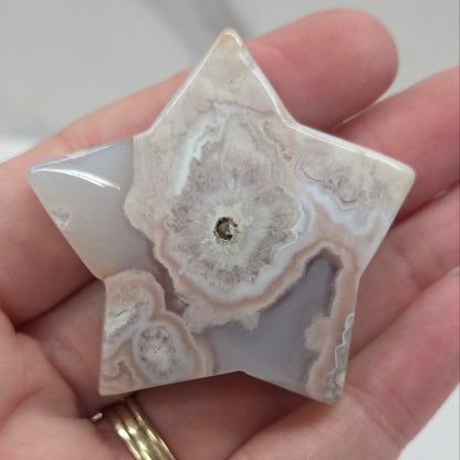 Hand holding a star-shaped agate stone against a white background