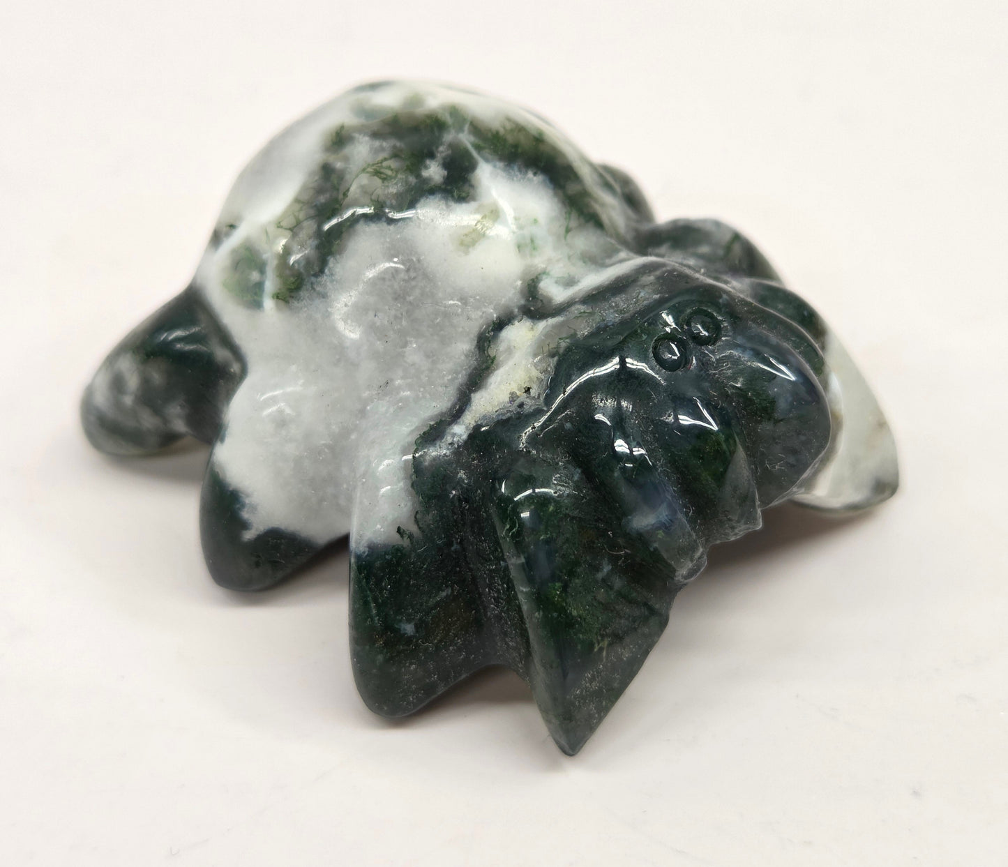 moss agate spider carving with grey agate and white and green inclusions on a white background