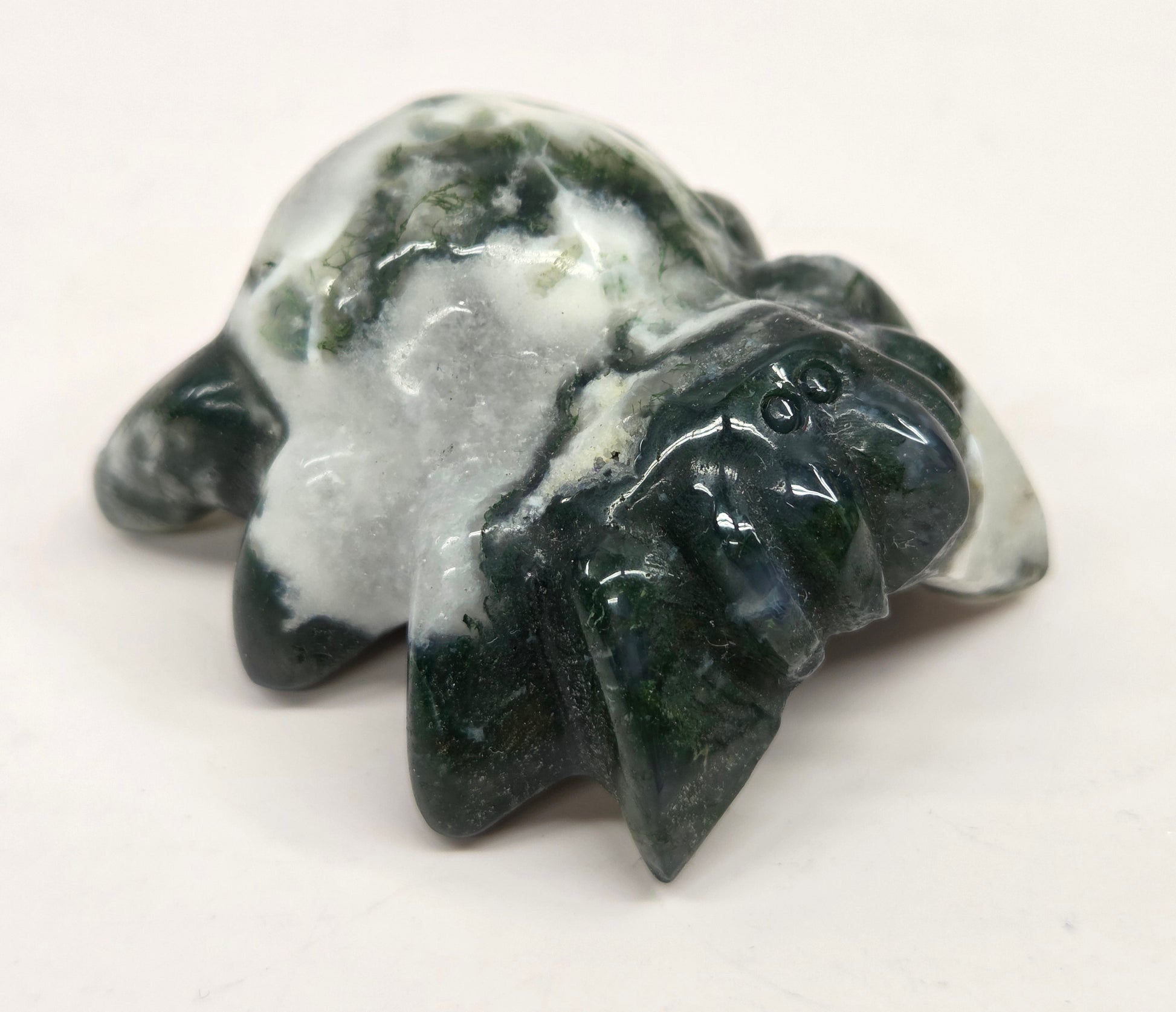 moss agate spider carving with grey agate and white and green inclusions on a white background